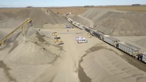 A busy quarry with machinery and conveyor belt, sunny day, aerial view