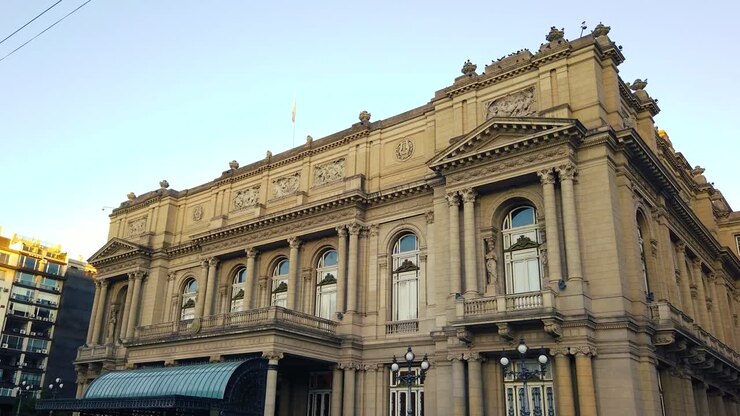 Teatro Colón al atardecer en Buenos Aires, Argentina, mostrando su icónica ópera y encanto cultural, con un paneo a la derecha y un suave resplandor azul en el cielo.