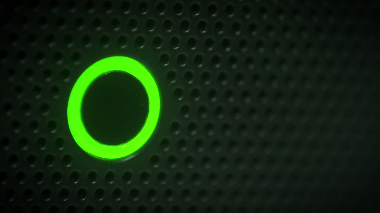 Glowing Power Indicator Light Changing Colors on a Dark Textured Surface