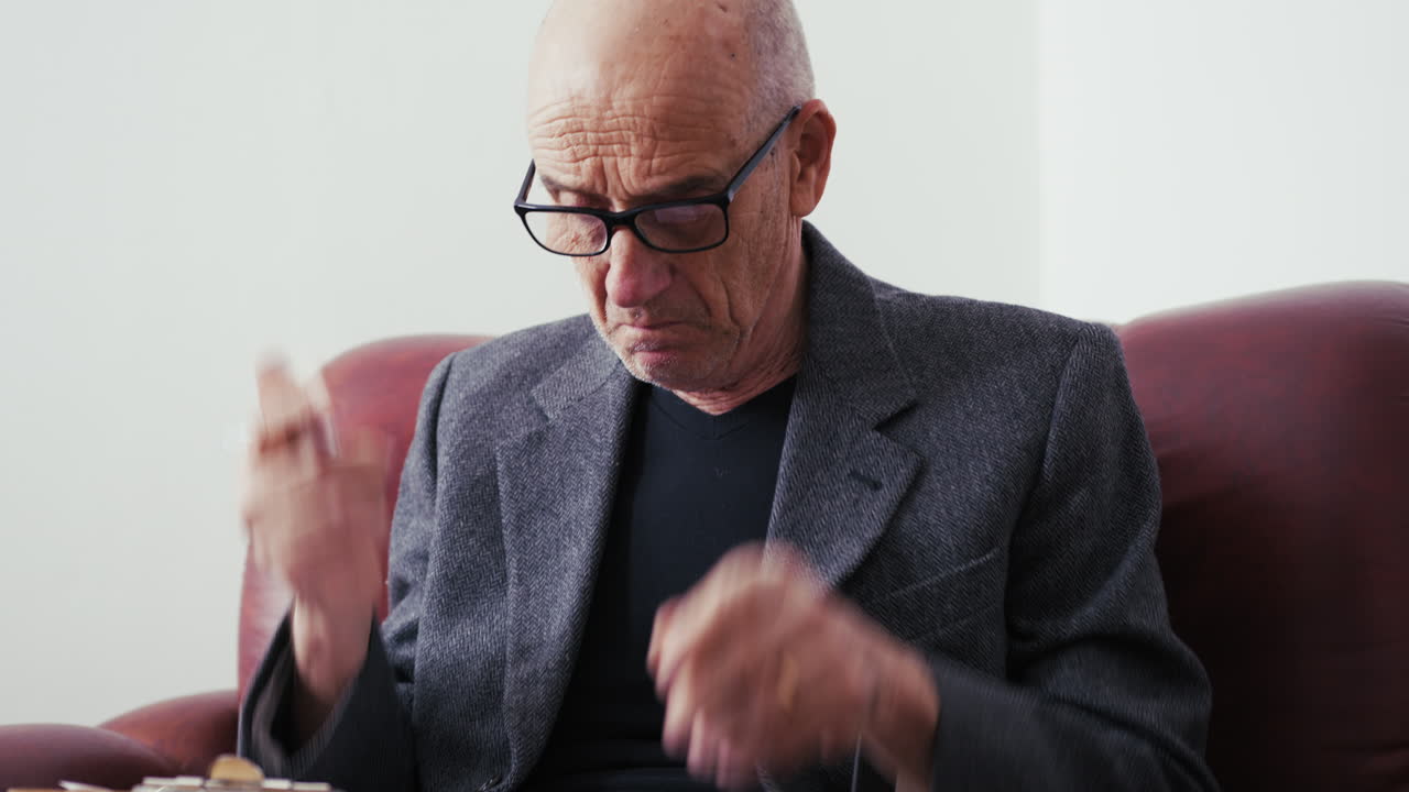 Old Man Sits on His Home Couch to Take Notes