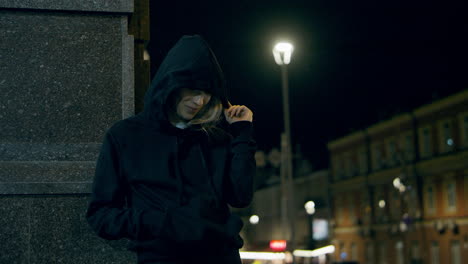 Smiling-woman-waiting-street-at-late-night-in-downtown-city-lights.