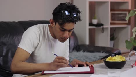 focused indian student studies at home for exams, highlighting on paper