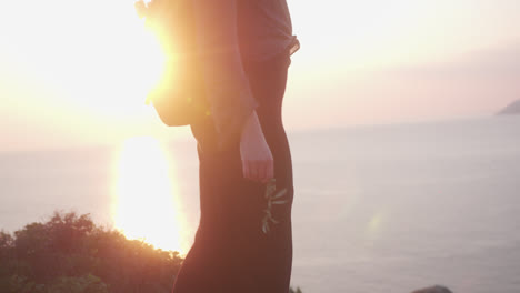 여성은 뒤에 일몰과 함께 바다 옆 언덕을 가로질러 걷는다