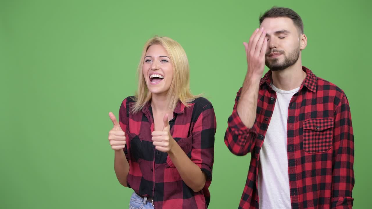 Young woman giving thumbs up with young man having headache together