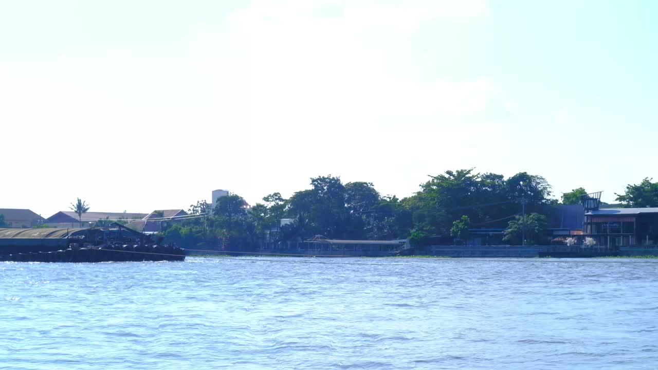 A tiny lead boat luging biggest and long pick-up floating on Chao Phraya River, Thailand.