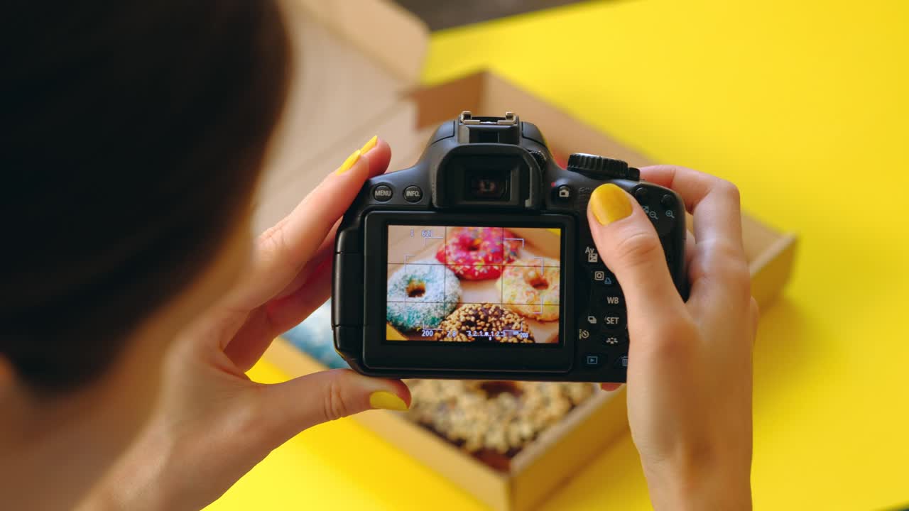 Woman's hands take pictures with photo camera of delicious donuts in box