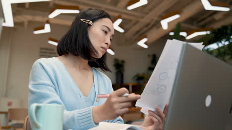 Una-Mujer-De-Negocios-Consultando-Documentos-De-Trabajo-En-Una-Cafetería