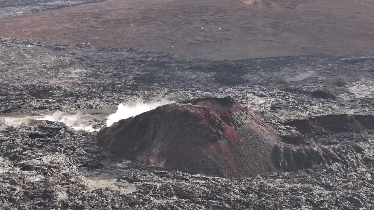 active volcanic mound releasing steam in rugged icelandic lava landscape
