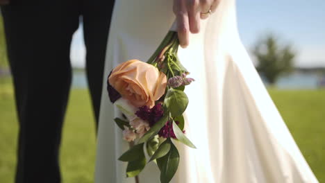 bride holding a colourful bouquet of flowers in a park