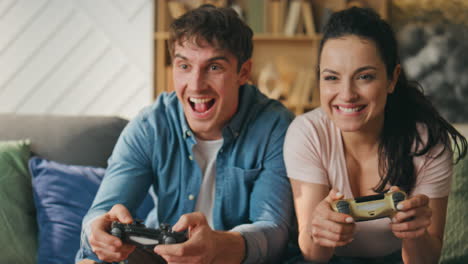 los jugadores sonrientes disfrutan de los videojuegos sentados en el sofá de cerca. pareja jugando en línea