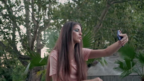 joven modelo tomando una selfie con plantas tropicales en el fondo
