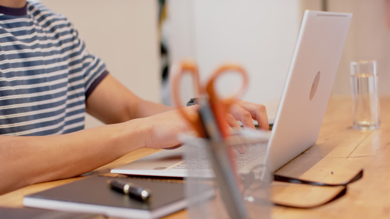 Biracial man working from home using laptop, slow motion