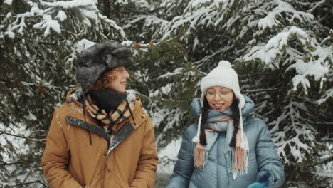 young women walking and talking in winter forest