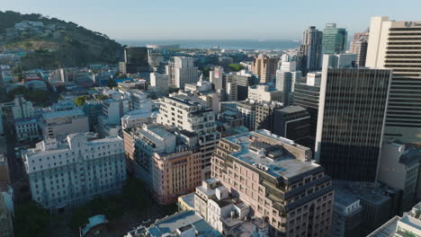 Fliegen-Sie-über-Moderne-Hochhäuser-Im-Stadtzentrum.-Meer-In-Der-Tafelbucht-Im-Hintergrund.-Kapstadt,-Süd-Afrika