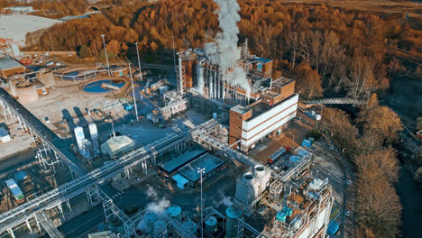 Aerial-footage-moving-towards-a-large-industrial-chemical-plant,-showing-pipelines,-metal-structures,-cooling-towers-and-chemical-storage