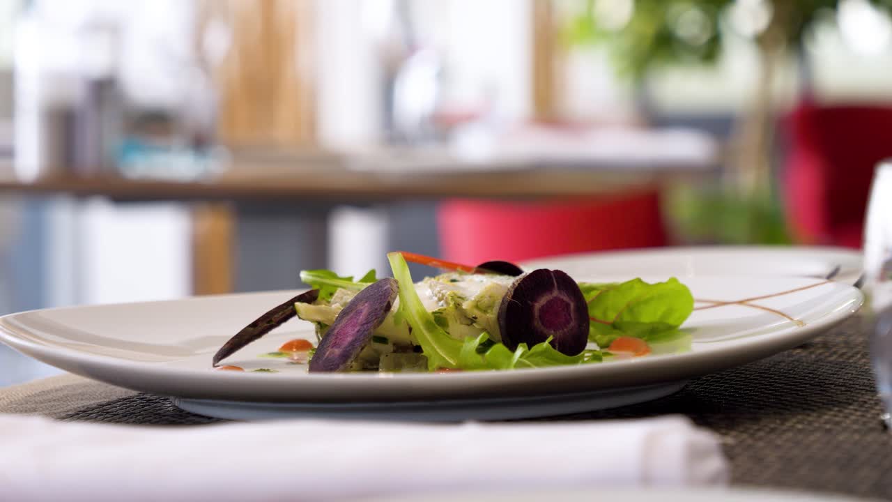 Ripresa lenta che rivela un'insalata mista splendidamente presentata, servita a tavola