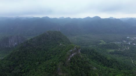 drone zoom in approaching misty limestone peaks covered in dense jungle vegetation in northern vietnam