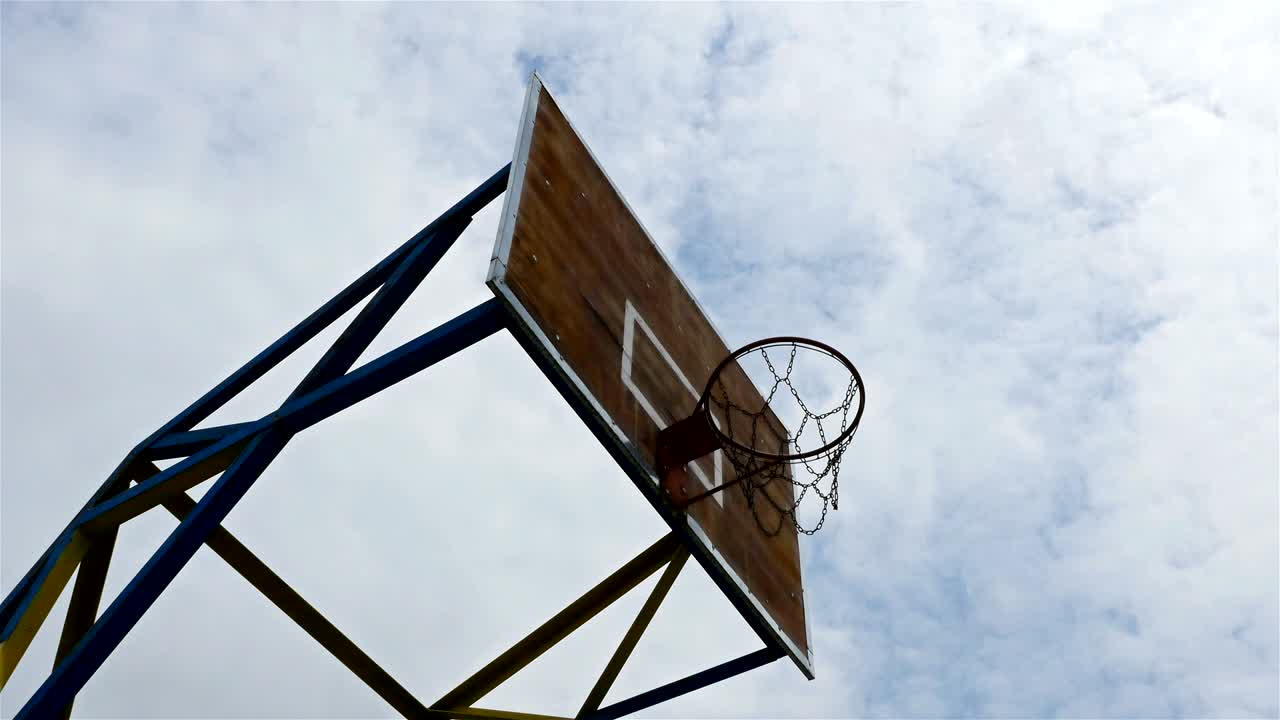 angulo bajo de lapso de tiempo del aro de baloncesto con nubes en movimiento en el cielo azul