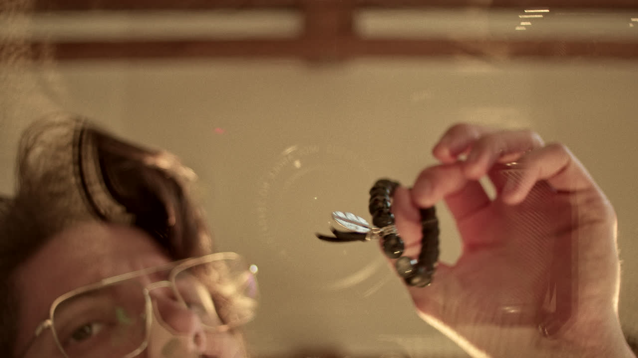 Reflection of a person holding a beaded bracelet