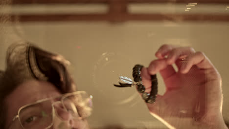 reflection of a person holding a beaded bracelet