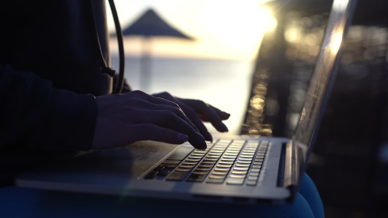 Young business woman using her laptop in cafe on sea background. Close up 4K
