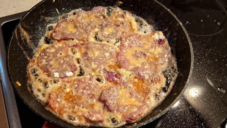 pan-frying meat patties in hot oil on the stove with bubbly edges and golden brown finish