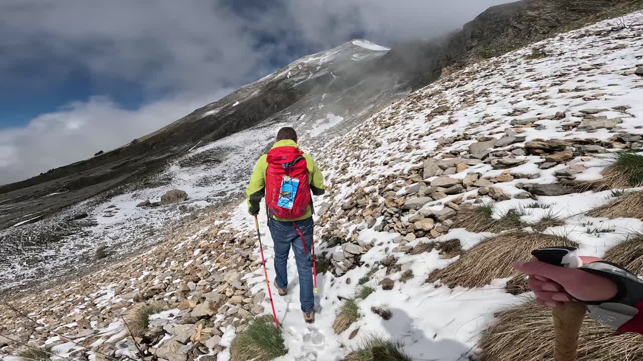 POV of hiking in rugged, snow-dusted mountain landscape on Alps