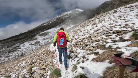 pov of hiking in rugged, snow-dusted mountain landscape on alps