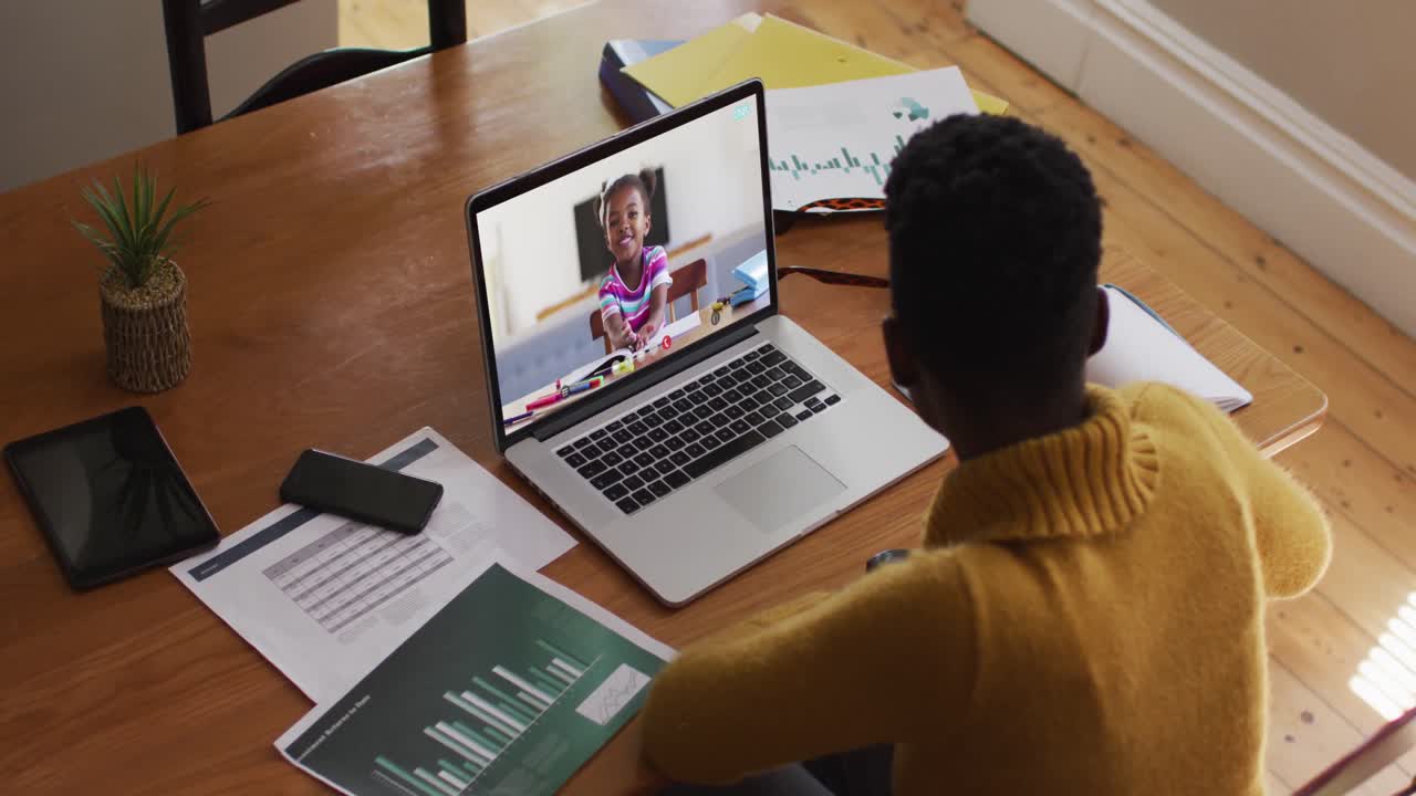 African american female teacher having a video call with school girl on laptop at home