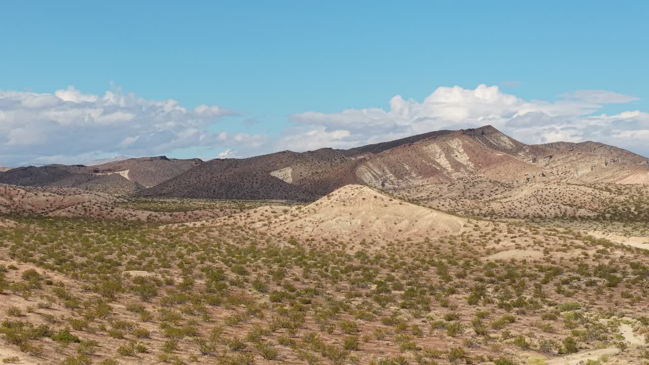 Arcing above the terrain, the aerial view reveals dramatic ridgelines and weathered formations glowing under the warm California sun