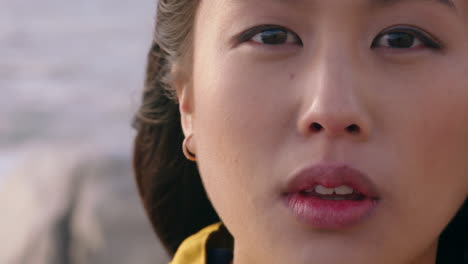 해가 지는 해변에서 자유를 탐험하는 심각한 독립적인 여성을 바라보는 해변에서 젊은 아시아 여성의 초상화