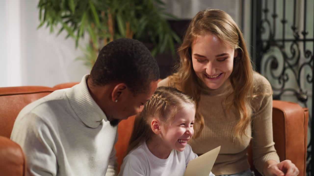 소녀 는 어머니 와 아버지 와 함께 오래된 사진 을 보고 웃는다