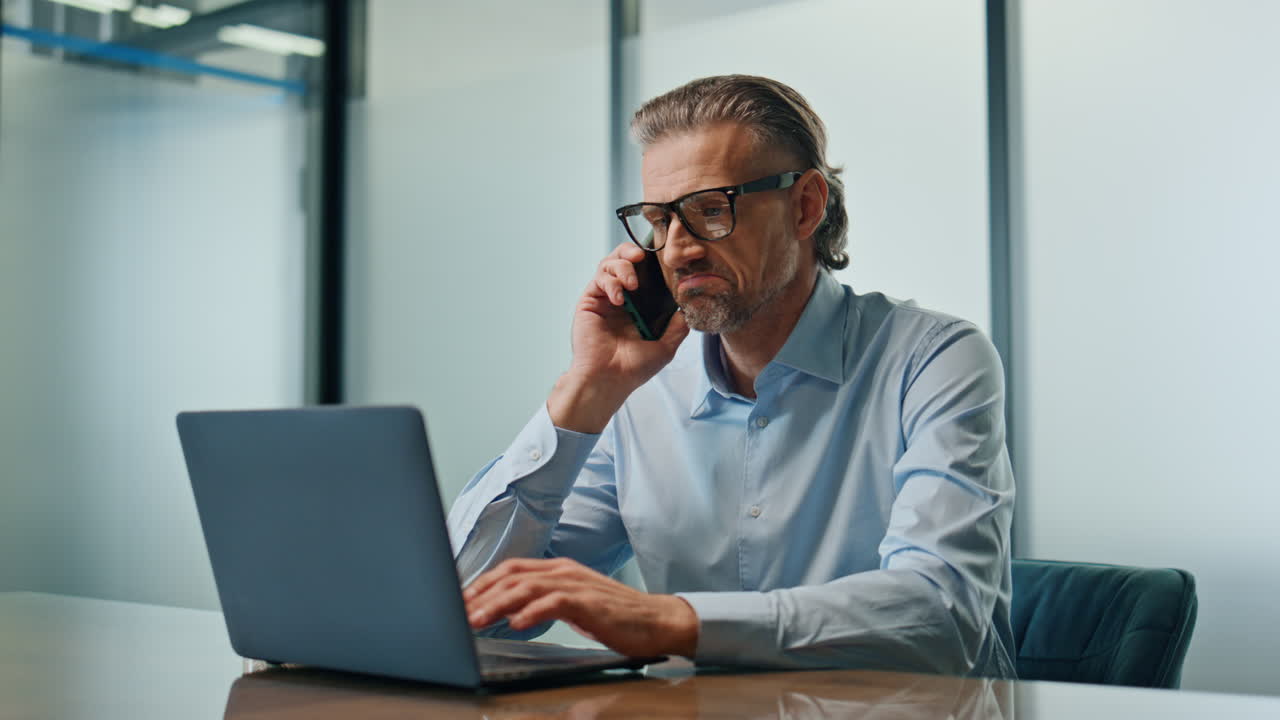 Uomo d'affari serio che parla al cellulare in ufficio. Direttore che chiama al telefono.