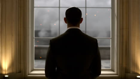 man in suit watches chaos unfold from a window