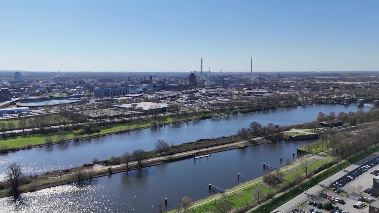 Vista aerea della città ad alta quota su canali, strade e corsi d'acqua con lo skyline di Duisburg e strutture industriali in lontananza