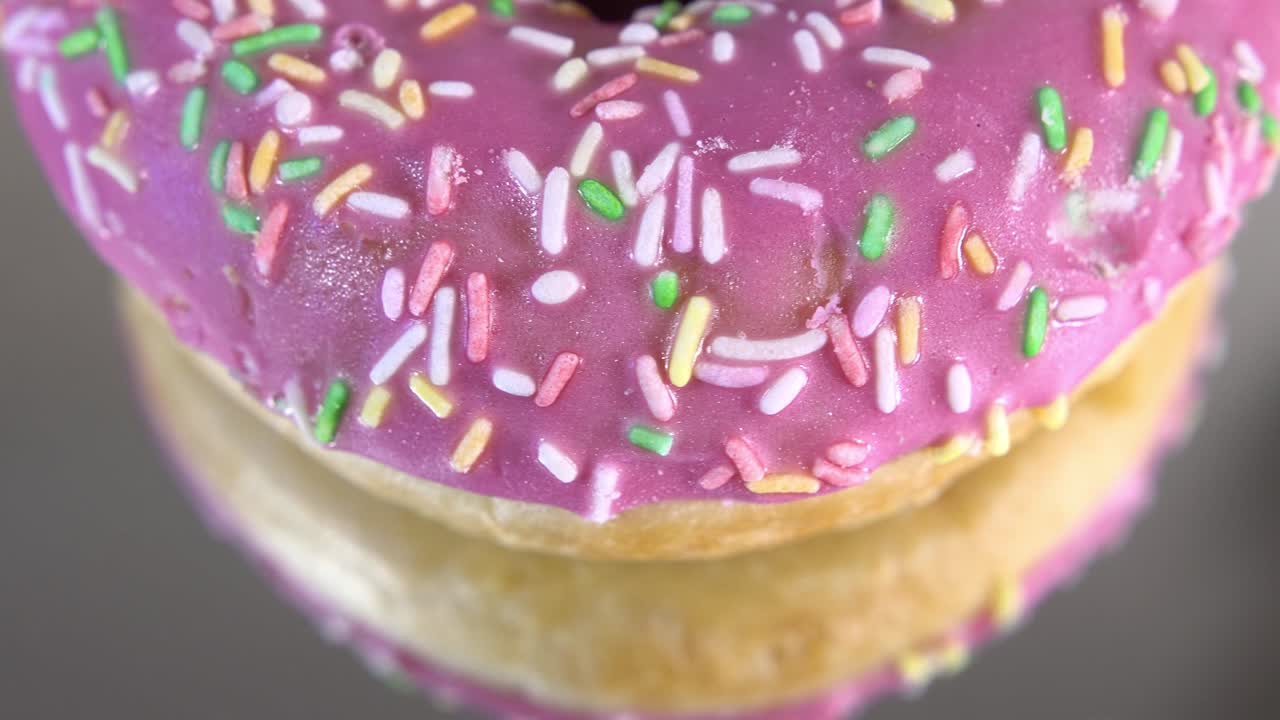 rosquillas giratorias con diferentes rellenos en la mesa del espejo. deliciosa rosquilla dulce girando en un plato. rosquilla brillante y colorida macro disparo de primer plano girando sobre un fondo blanco. bucle sin costuras.