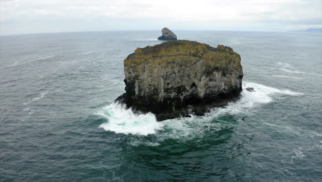 large sea stack in choppy ocean with distant horizon