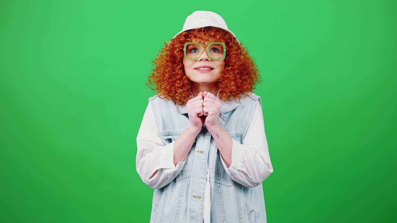 Young believing redhead curly lady wearing eyeglasses and panama hat making cherished wish, begging and pleading