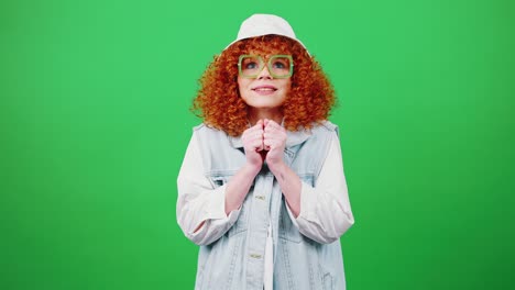 joven creyente pelirroja mujer rizada con gafas y sombrero de panama haciendo un deseo querido, suplicando y suplicando