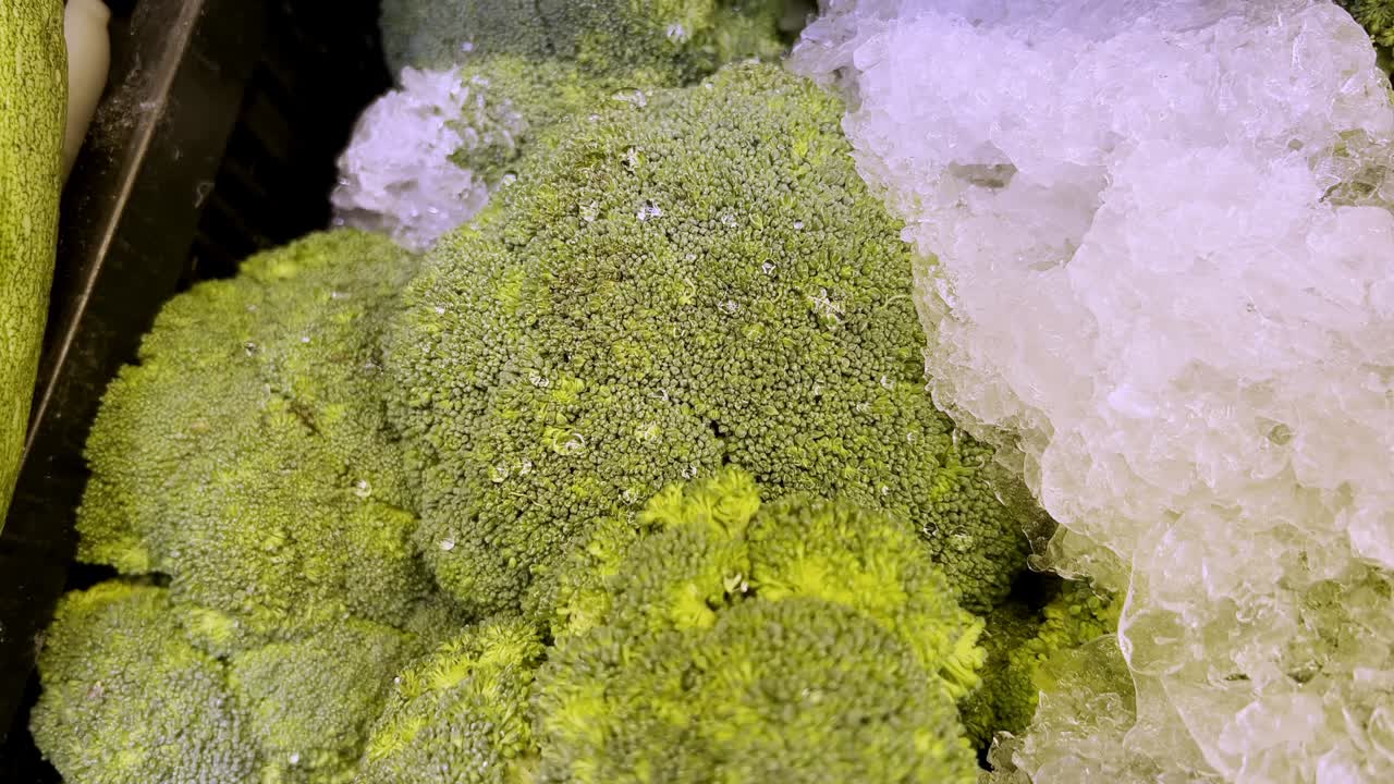 las cabezas de brócoli frescas se enfrían en hielo en una vitrina de supermercado, listas para la compra, ofreciendo una opción de verduras verdes saludables y vibrantes