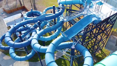 una compleja estructura de tobogán de agua azul en un parque al aire libre rodeado de hierba