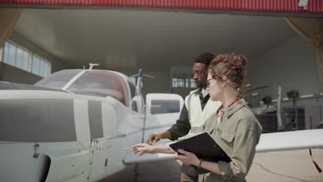 inspector discussing aircraft exterior with technician outside hangar