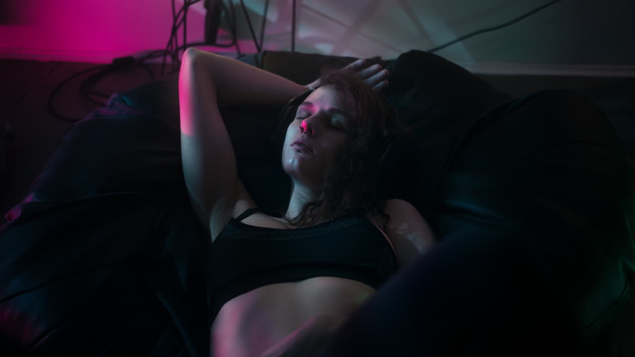 Primo piano di una ragazza che dorme su un pouf mentre ascolta la musica