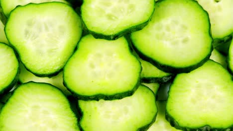 sliced pieces of green cucumber stacked on a hill rotate. fresh sliced cucumber pieces are rotating on white background