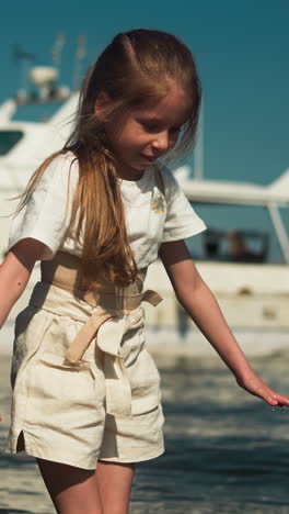 playful girl with corset to straighten back walks and boy knee-deep in sea against large yacht on sunny day. family rest on summer vacation together