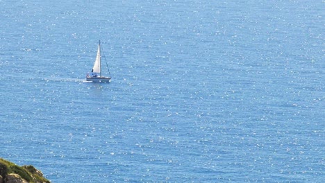 sailboat sailing on a sparkling blue sea, coast of spain, zoom