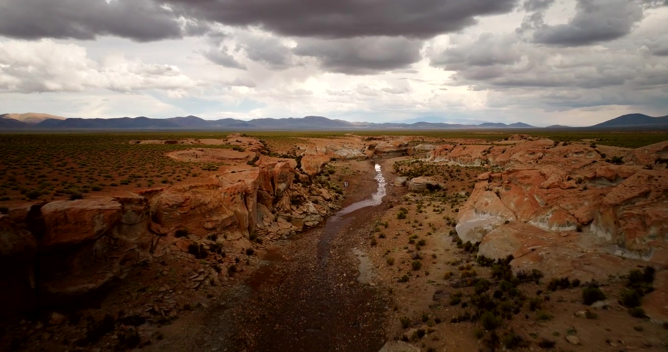 Small stream flows through jagged river valley in Bolivia Siloli desert, aerial