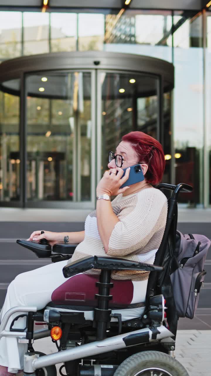 Happy Woman in Motorized Wheelchair Talking on Smartphone in City