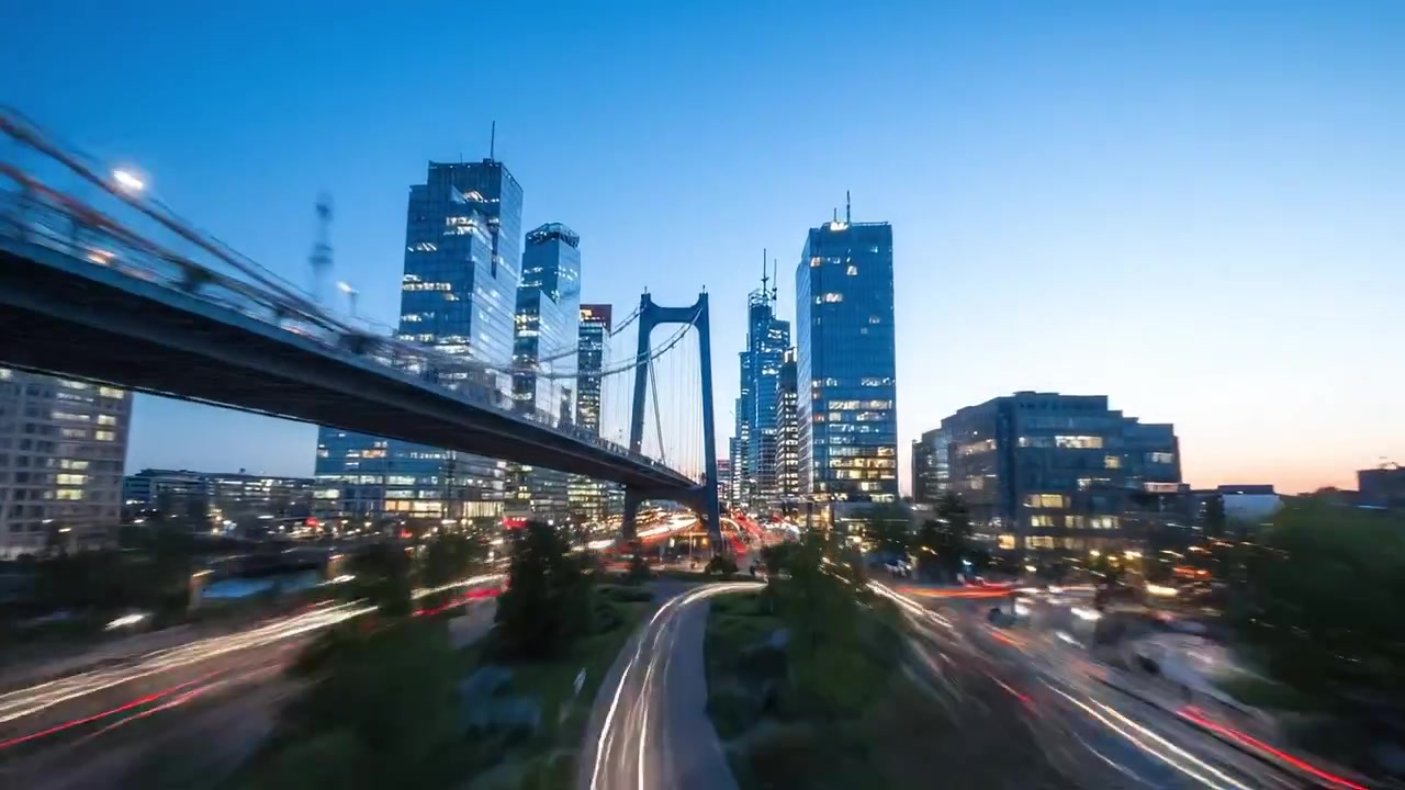 Urbane Dämmerung: Ein spektakuläres Stadtbild, eingefangen unter der Brücke, mit lebendigen Lichtern und fließendem Verkehr, während die Nacht über einer modernen Stadtsilhouette hereinbricht.