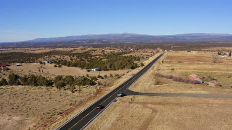 Vista-Superior-Aérea-De-Dos-Autos-Que-Circulan-Por-Una-Carretera-En-Norwood,-Colorado